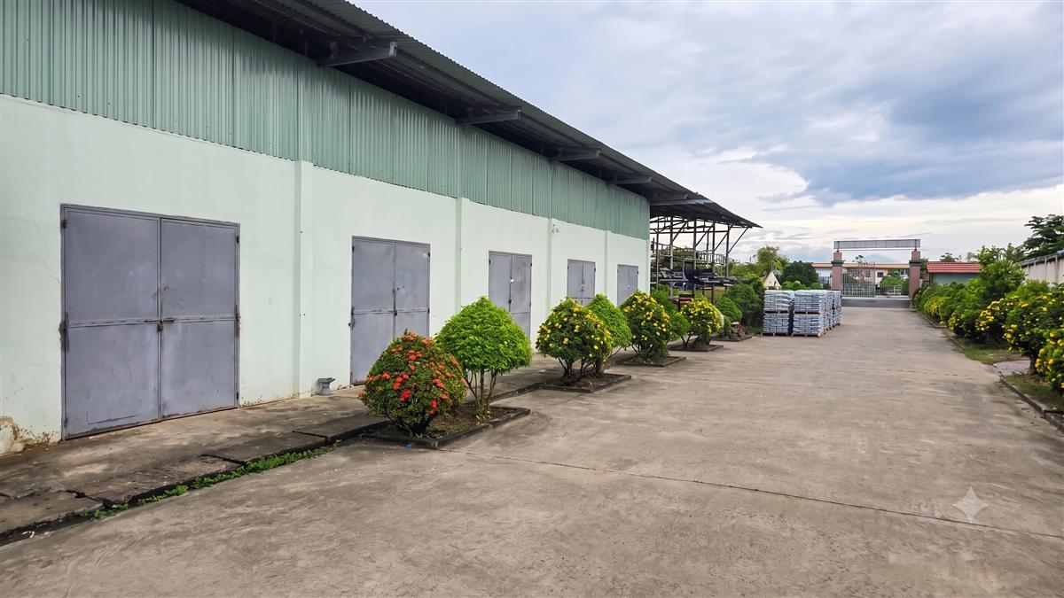 Dãy kho vật tư với cửa sắt và vật tư xếp trên pallet ngoài sân